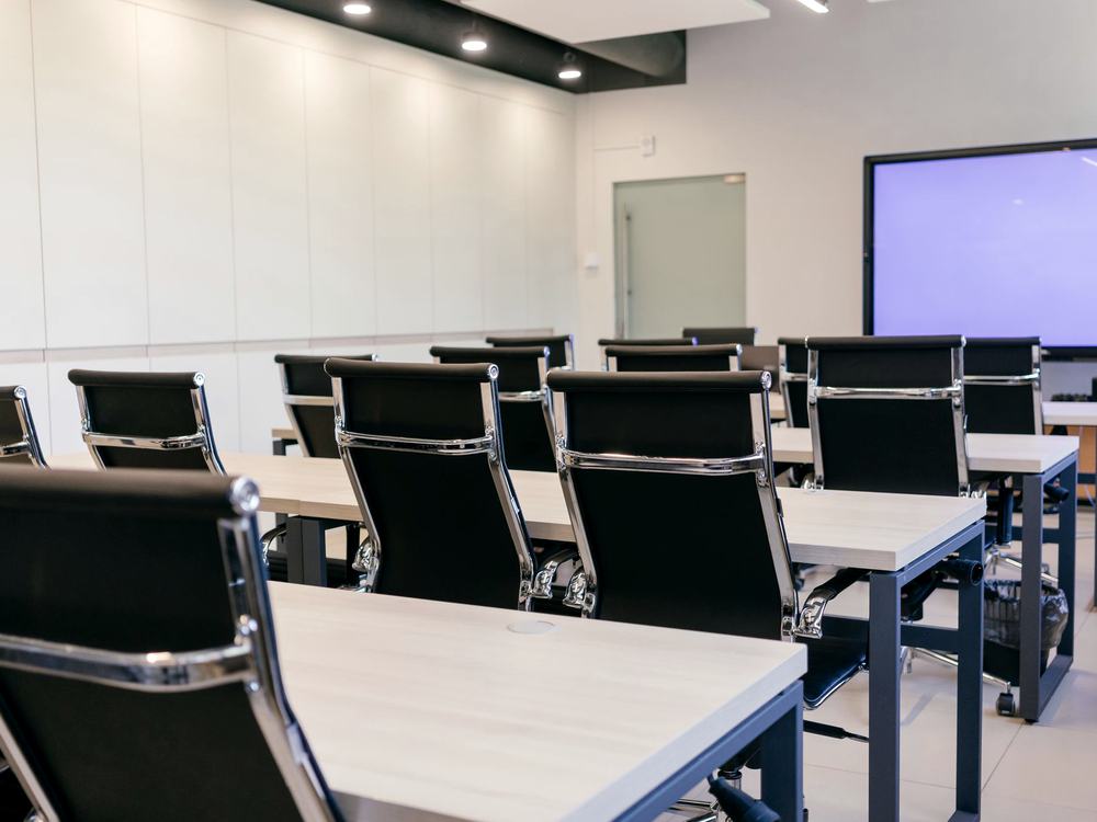 Rows of desks and task chairs in an institutional training room.