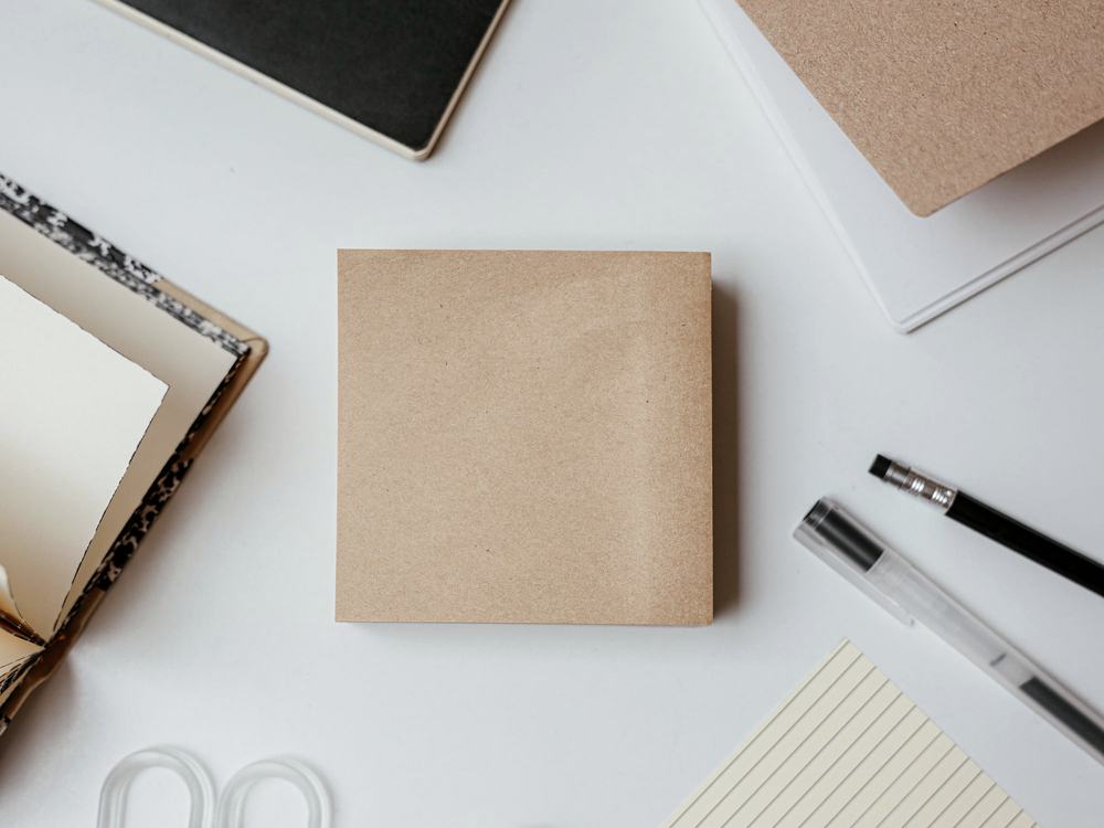 Notebooks, note pads, pens and desk accessories arranged on a light work surface.