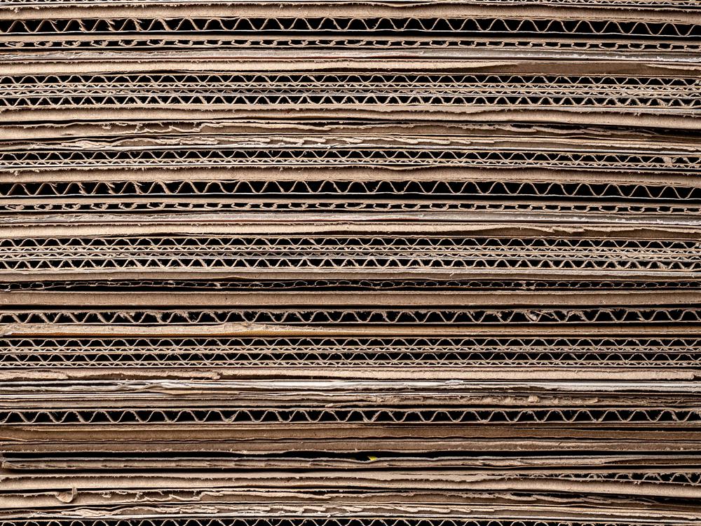 Stacked sheets of corrugated cardboard seen from the side, showing the fluted core.