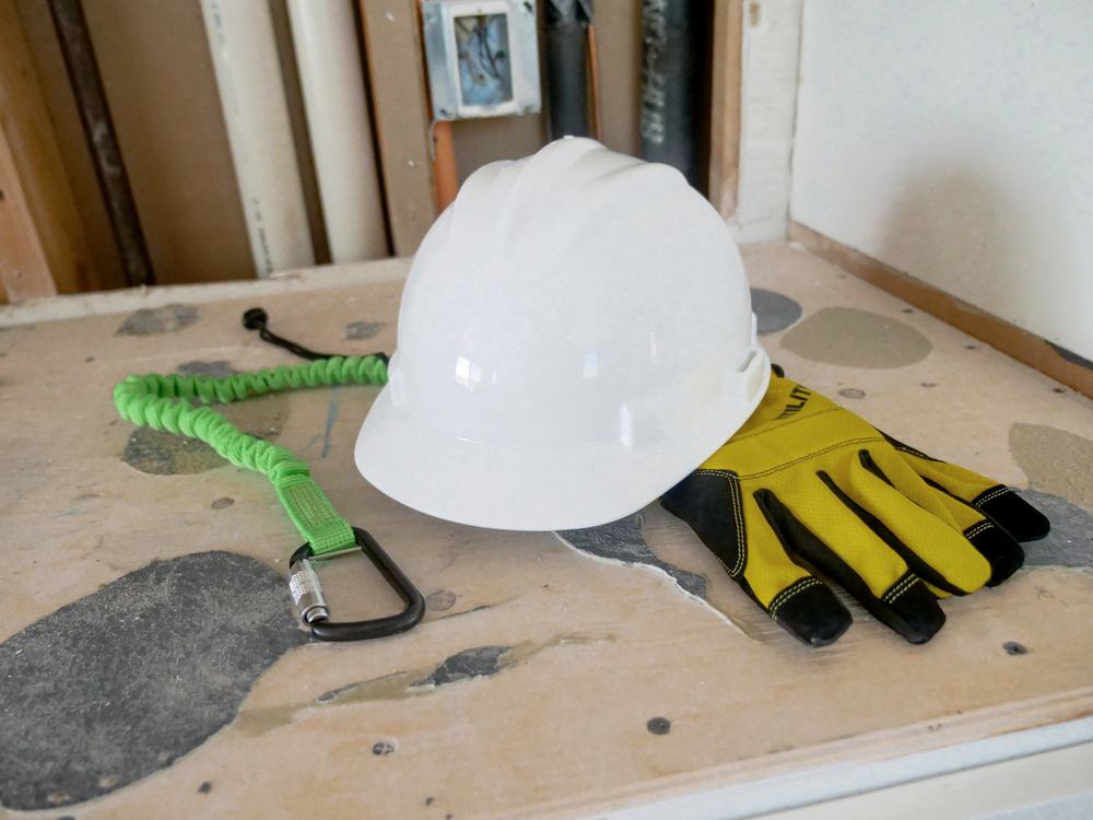 A hard hat and a pair of work gloves resting on a workbench.