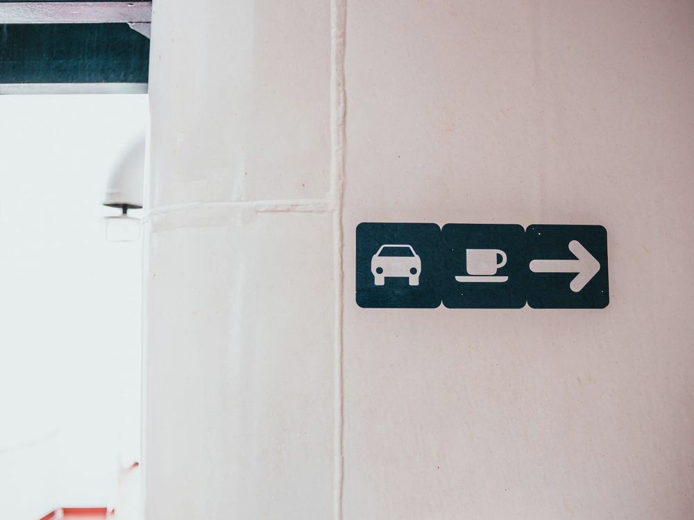 A wall-mounted wayfinding sign with pictograms and a directional arrow.