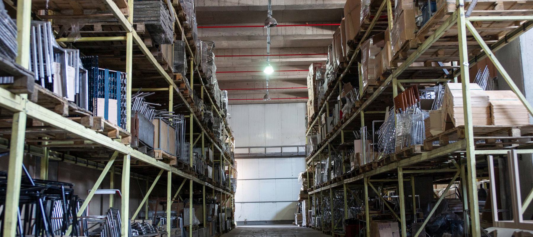 Aisle of pallet racking in a distribution warehouse, stacked with cartons and palletized goods.