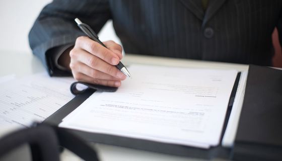 Shipping and customs paperwork being completed and signed on a clipboard.