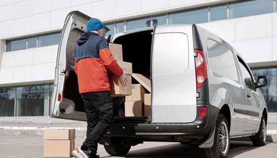 Cartons being loaded into a delivery van at a loading bay.