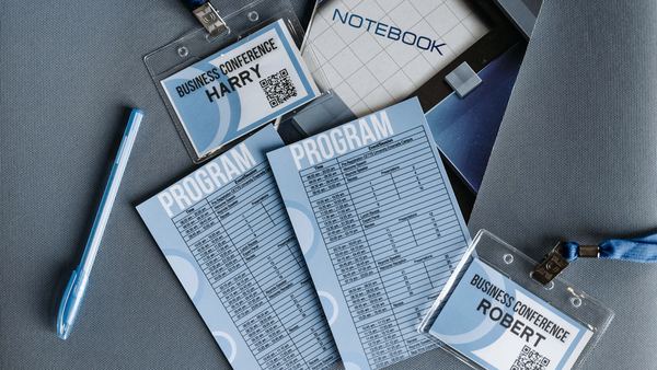 Conference name badges, printed programs and a notebook laid out on a table.