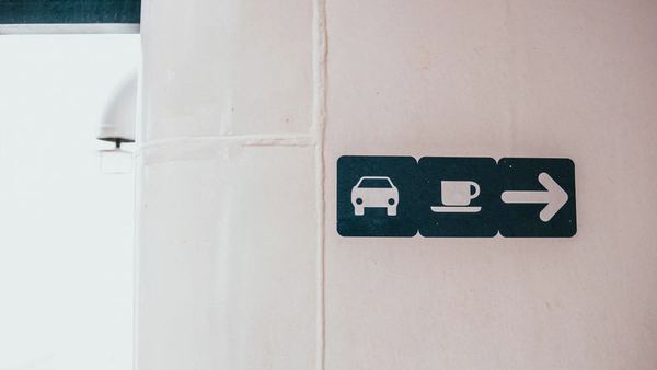 A wall-mounted wayfinding sign with pictograms and a directional arrow.