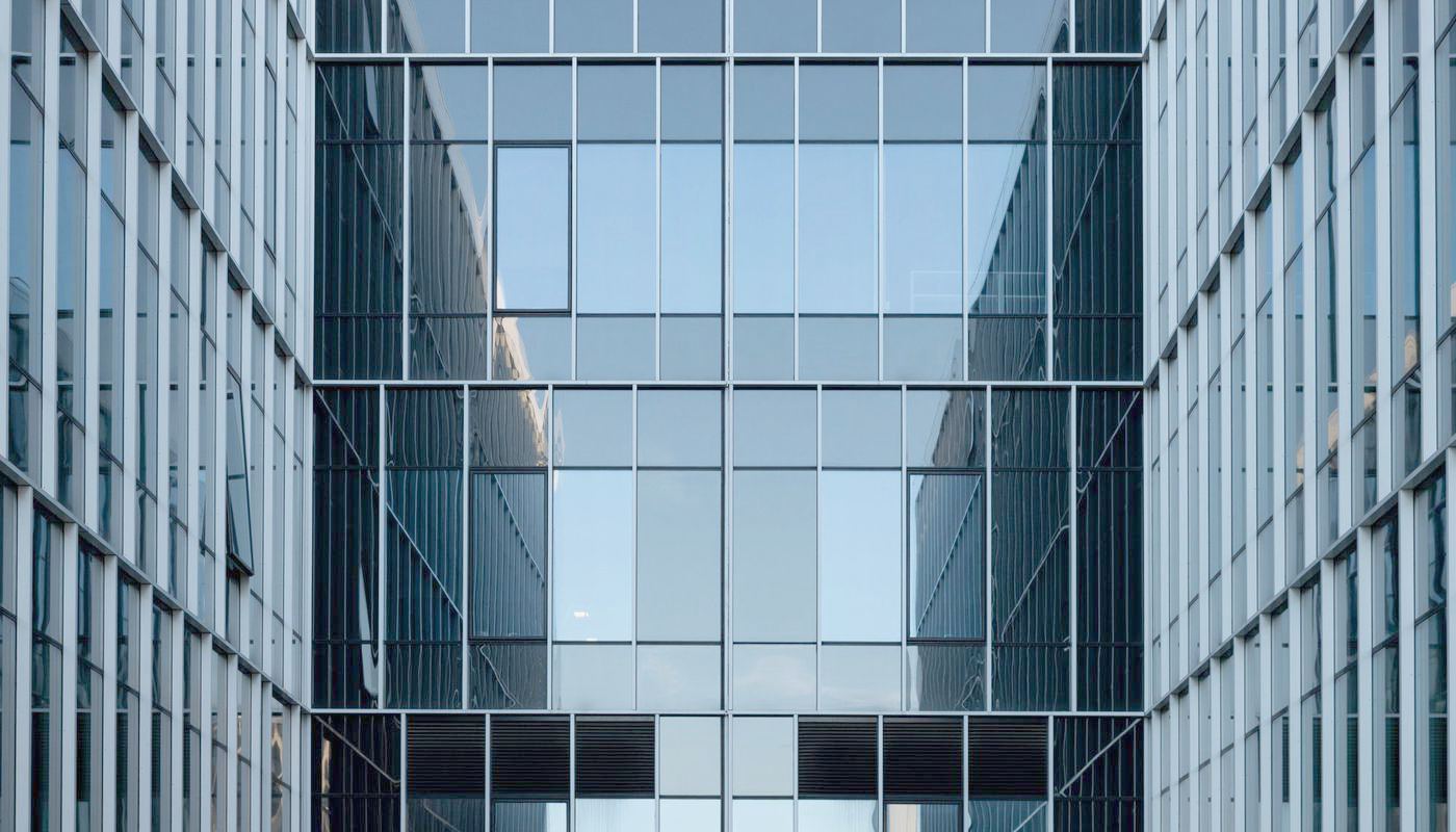 Glass and steel office buildings in a commercial district, seen from street level.